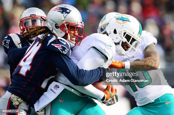 Stephon Gilmore of the New England Patriots tackles DeVante Parker of the Miami Dolphins during the game at Gillette Stadium on November 26, 2017 in...