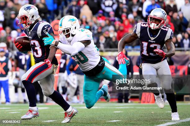 Dion Lewis of the New England Patriots is tackled by Reshad Jones of the Miami Dolphins during a game at Gillette Stadium on November 26, 2017 in...