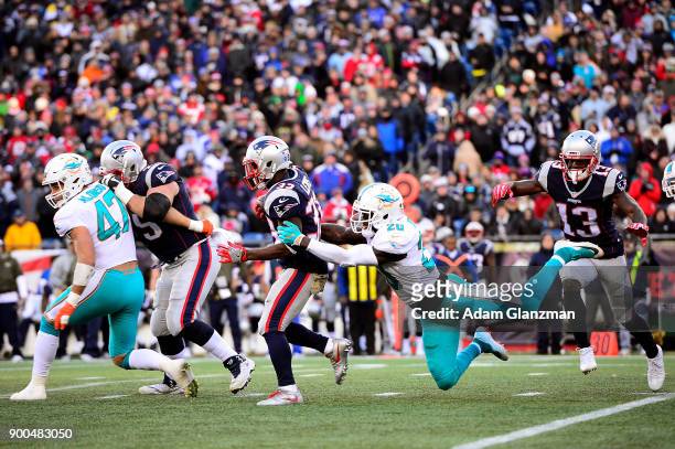 Dion Lewis of the New England Patriots is tackled by Reshad Jones of the Miami Dolphins during a game at Gillette Stadium on November 26, 2017 in...