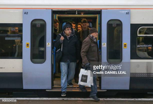 Commuters exit a train at Victoria station, in central London on January 2, 2018. - As the price of an average ticket rose by 3.4 percent on January...