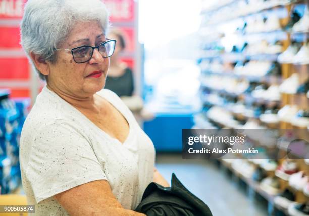 a mulher de sênior ativa de cabelos prateados 65 anos de idade e sua neta adolescente compras na loja de varejo shouse - 65 69 years - fotografias e filmes do acervo