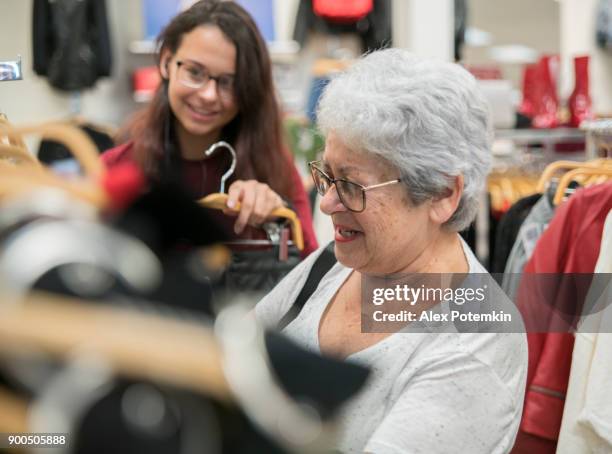 la femme senior active argentée de 65 ans et sa petite-fille adolescent, faire du shopping dans le magasin de vente au détail de vêtements - 14 years old photos et images de collection