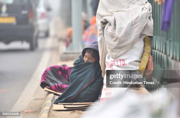 People brave through a cold weather amid heavy fog at Mother Crescent Marg, on January 2, 2018 in New Delhi, India. Cold wave conditions continued to...