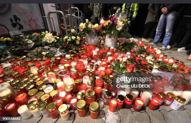 Picture taken on January 2, 2018 shows candles and flowers displayed outside a grocery store where a 15-year-old girl was stabbed to death by her...