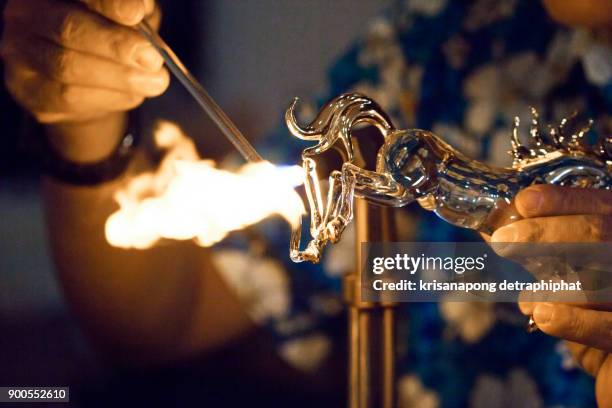 glassblower heats the glass piece for shaping the future christmas ornament - plasma ball foto e immagini stock