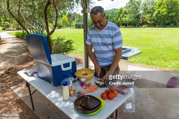 australische aborigines mann vorbereiten, ein bbq in einem öffentlichen park zu kochen - bbq australia stock-fotos und bilder