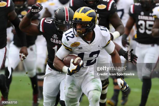 Michigan Wolverines running back Chris Evans tries to break a tackle from South Carolina Gamecocks linebacker Skai Moore during the 2018 Outback Bowl...