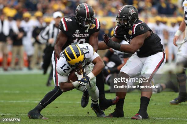 Michigan Wolverines running back Chris Evans is tackled by South Carolina Gamecocks linebacker Skai Moore and South Carolina Gamecocks defensive...