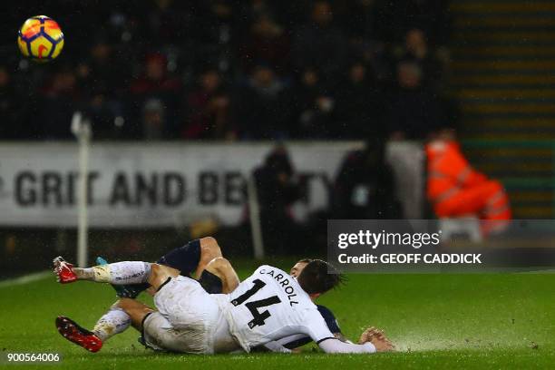 Swansea City's English midfielder Tom Carroll slides into a tackle with with Tottenham Hotspur's English defender Kieran Trippier during the English...