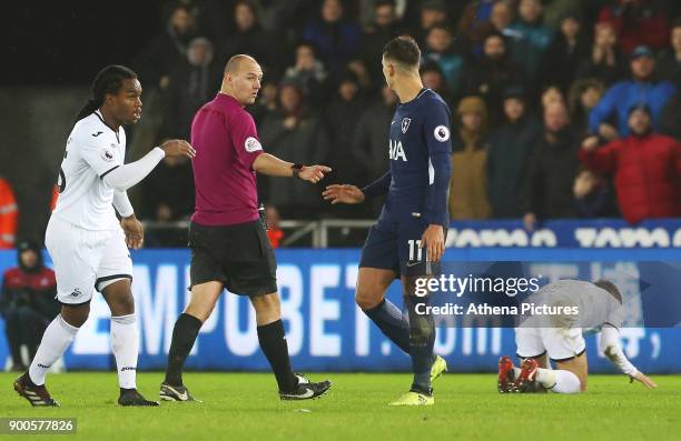 Referee Bobby Madley calls Erik Lamela of Tottenham Hotspur over for a yellow card after a challenge on Tom Carroll of Swansea City during the...