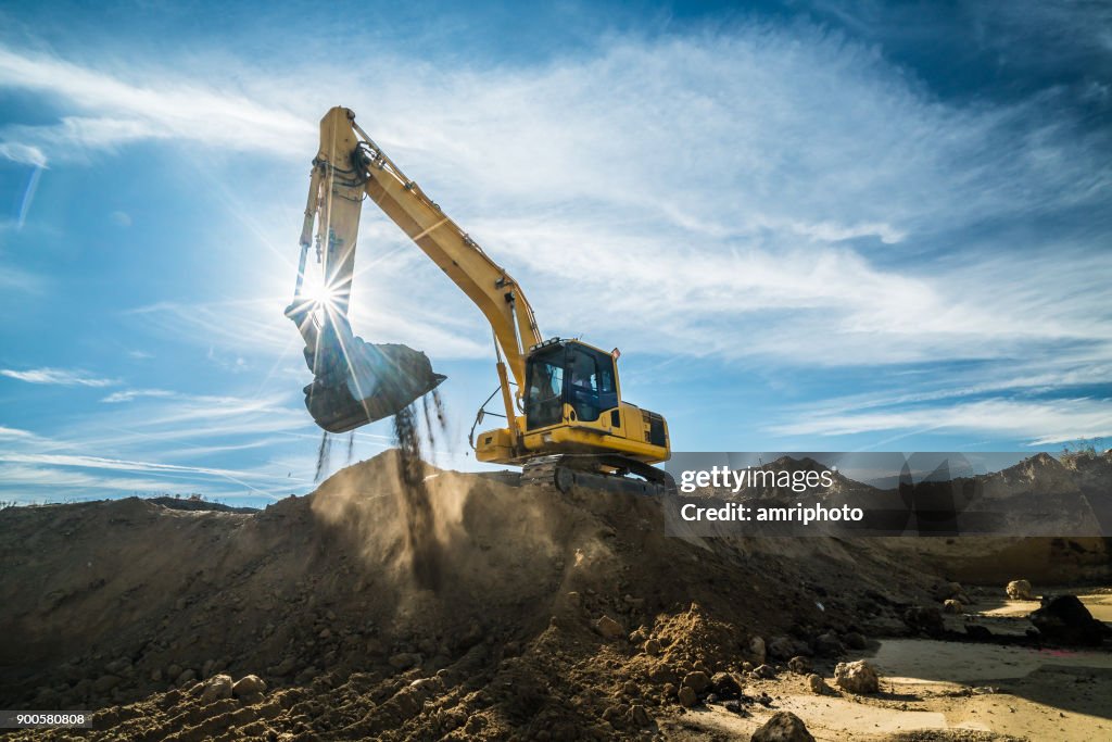 Construction - digger working at building site on sunny day