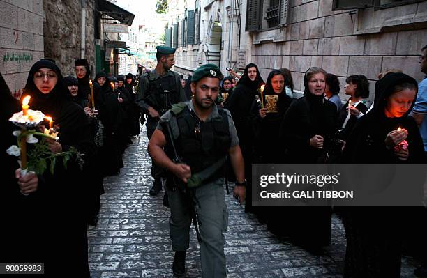 Israeli soldiers walk past Christian Orthodox nuns holding candles and flowers as they take part in a religious procession on August 25, 2009 along...