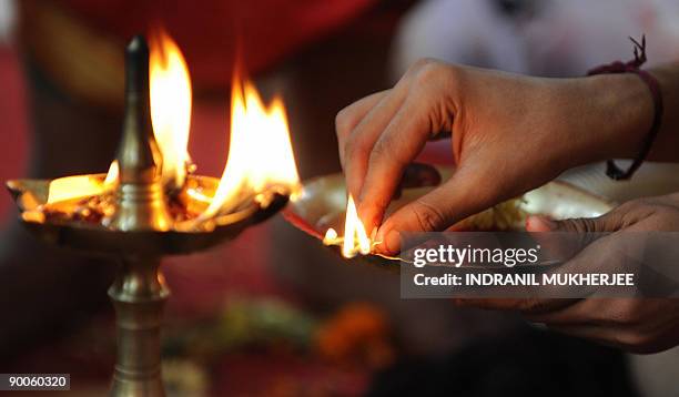 Volunteer lights a wick from a holy fire during the 'Tulabharam' - a Hindu ritual during which an offering equivalent to a person's weight in coins,...