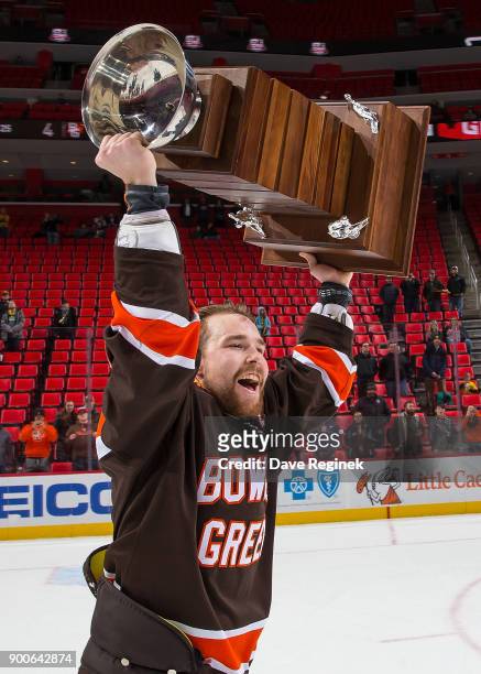 Captain Mitchell McLain of the Bowling Green Falcons lifts the John MacInnes Cup after winning the championship game of the Great Lakes Invitational...