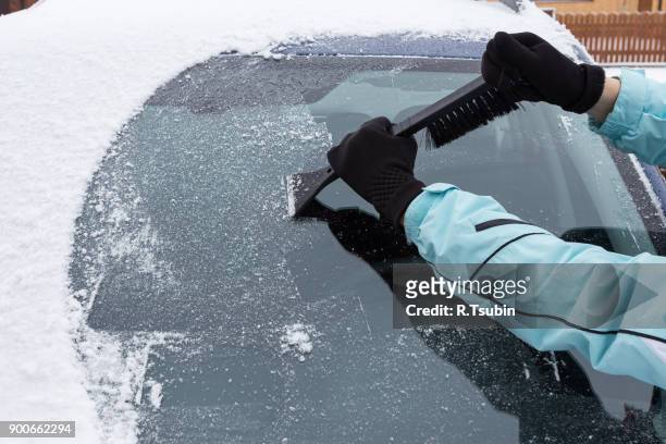 woman cleaning snow from the car - winter car window stock-fotos und bilder