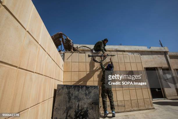 Syrian Democratic Force fighters hand off an RPG to be fired at the National Hospital, a key position which was held by Islamic State jihadists along...