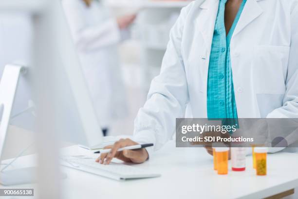 pharmacy checking computer while filling prescription for customer - filling stock pictures, royalty-free photos & images