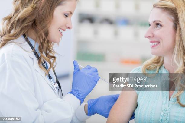 nurse or pharmacist giving customer in pharmacy a flu shot - pharmacy vaccination stock pictures, royalty-free photos & images