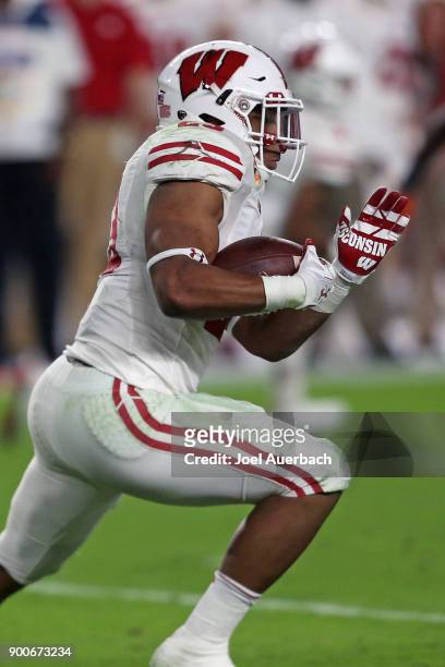 Jonathan Taylor of the Wisconsin Badgers runs with the ball against the Miami Hurricanes during the 2017 Capital One Orange Bowl at Hard Rock Stadium...