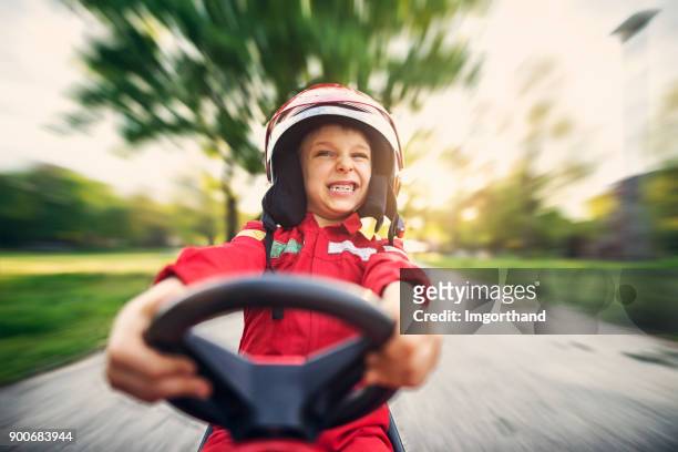 ritratto del bambino che guida velocemente la sua auto giocattolo - pilota di auto da corsa foto e immagini stock