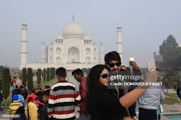 Visitors take a selfie photograph in front of the Taj Mahal in Agra on January 3, 2018. India is to restrict the number of daily visitors to the Taj...