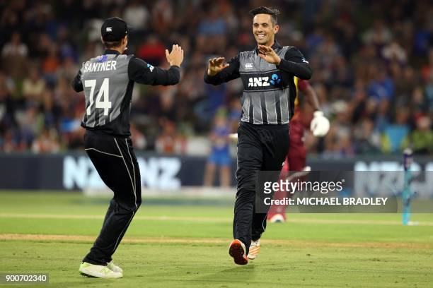 New Zealand's Anaru Kitchen celebrates with Mitchell Santner after taking the wicket of West Indies batsman Rovman Powell during the third Twenty20...