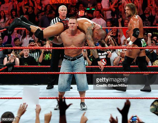 Wrestler John Cena picks up wrestler Randy Orton as wrestler Triple H looks on during the WWE Monday Night Raw show at the Thomas & Mack Center...