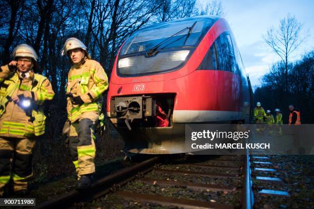 Firemen stand in front of a regional train that partly derailed after it collided with a tree uprooted by stormy depression named "Burglind" on...