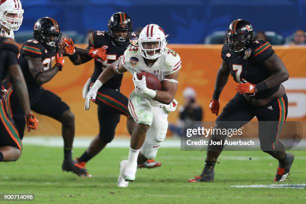 Jonathan Taylor of the Wisconsin Badgers runs with the ball against the Miami Hurricanes during the 2017 Capital One Orange Bowl at Hard Rock Stadium...