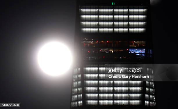 The supermoon rises next to One World Trade Center as people look out the windows of the observatory in New York City on January 1, 2018 as seen from...