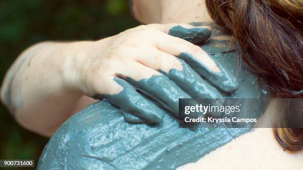 woman applying volcanic mud treatment on shoulders - ollas de barro fotografías e imágenes de stock