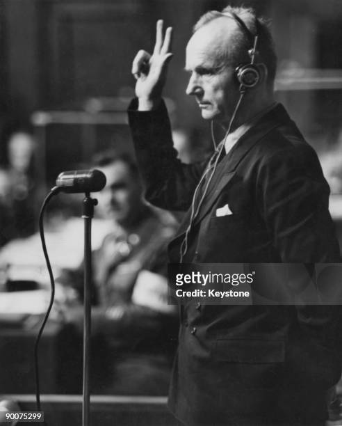 German naval commander Karl Donitz raises his hand in oath before taking the witness stand at the International Military Tribunal at the Palace of...