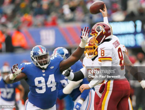 Quarterback Kirk Cousins of the Washington Redskins has to throw the ball away as he is under pressure by Dalvin Tomlinson of the New York Giants in...
