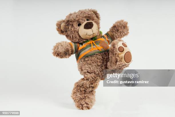brown stuffed bear kicking - bambola giocattolo foto e immagini stock