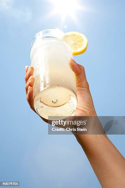 woman holding a glass of lemonade - sunlight through drink glass stock-fotos und bilder