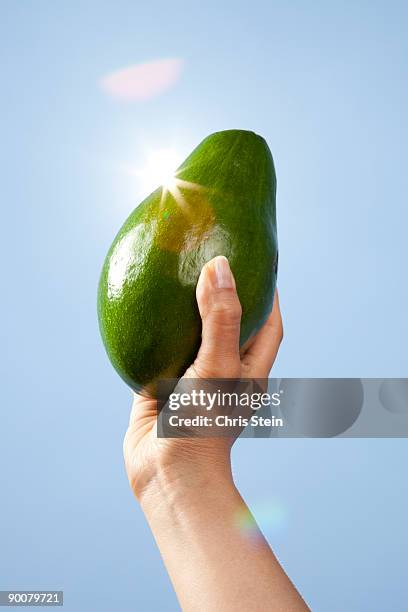 woman holding avocado - hochhalten stock-fotos und bilder