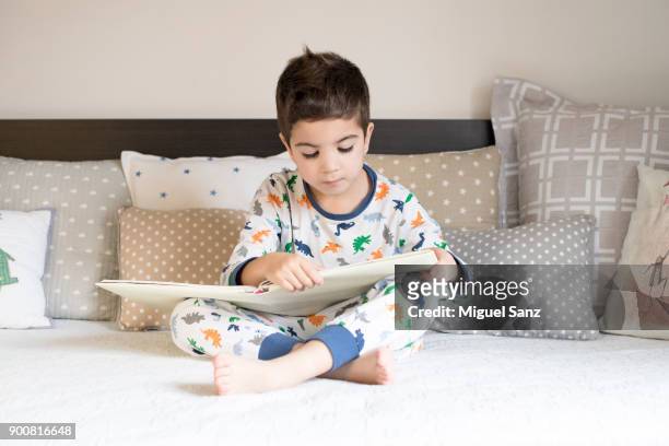 little boy reading book on bed - moving down to seated position stock pictures, royalty-free photos & images