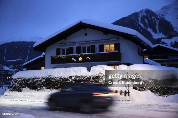 An automobile drives past a residential property illuminated at dusk in Klosters, Switzerland, on Saturday, Dec. 30, 2017. The supply of uninhabited...