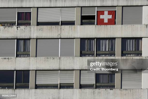 Swiss national flag hangs in a window of a residential apartment block in Bern, Switzerland, on Monday, Jan. 1, 2018. The supply of uninhabited...