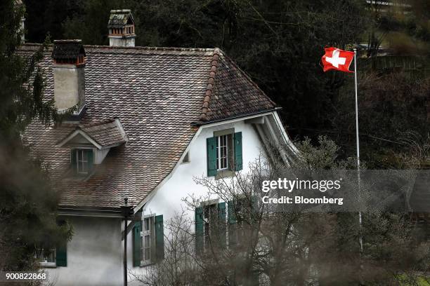 Swiss national flag flies outside a traditional residential property in Bern, Switzerland, on Monday, Jan. 1, 2018. The supply of uninhabited...