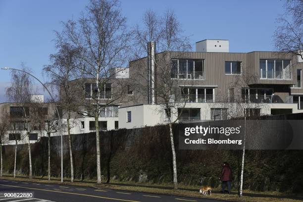 Pedestrian walks a dog past residential apartments in Bern, Switzerland, on Monday, Jan. 1, 2018. The supply of uninhabited apartments for rent has...