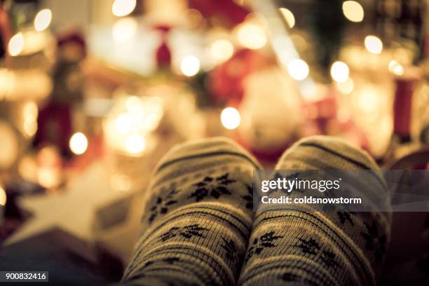 nahaufnahme eines füßen warme gemütliche skandinavischen stil weihnachten socken unter beleuchtete weihnachtsbaum - fashion close up stock-fotos und bilder