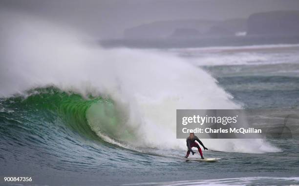 Surfer Al Mennie catches a wave at east strand beach after Storm Eleanor recorded winds of up to 90mph on January 3, 2018 in Portrush, Northern...