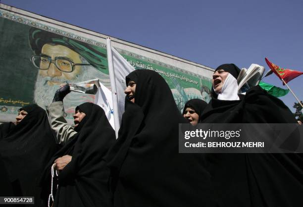 Iranian women chant slogans under a portrait of Iran's supreme leader Ali Khamenei during a demonstration to protest against women who violate the...