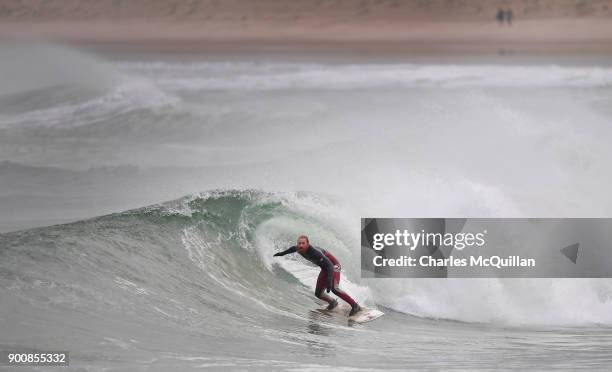 Surfer Al Mennie catches a wave at east strand beach after Storm Eleanor recorded winds of up to 90mph on January 3, 2018 in Portrush, Northern...