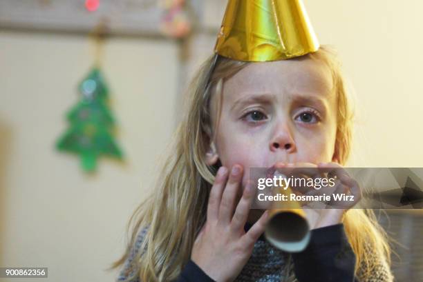 girl of five wearing golden hat, blowing party paper horn - whistle blowing stock pictures, royalty-free photos & images