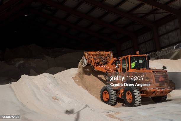 City sanitation worker uses a backhoe to pile up road salt at a storage depot on the Lower East Side, January 3, 2018 in New York City. New York City...