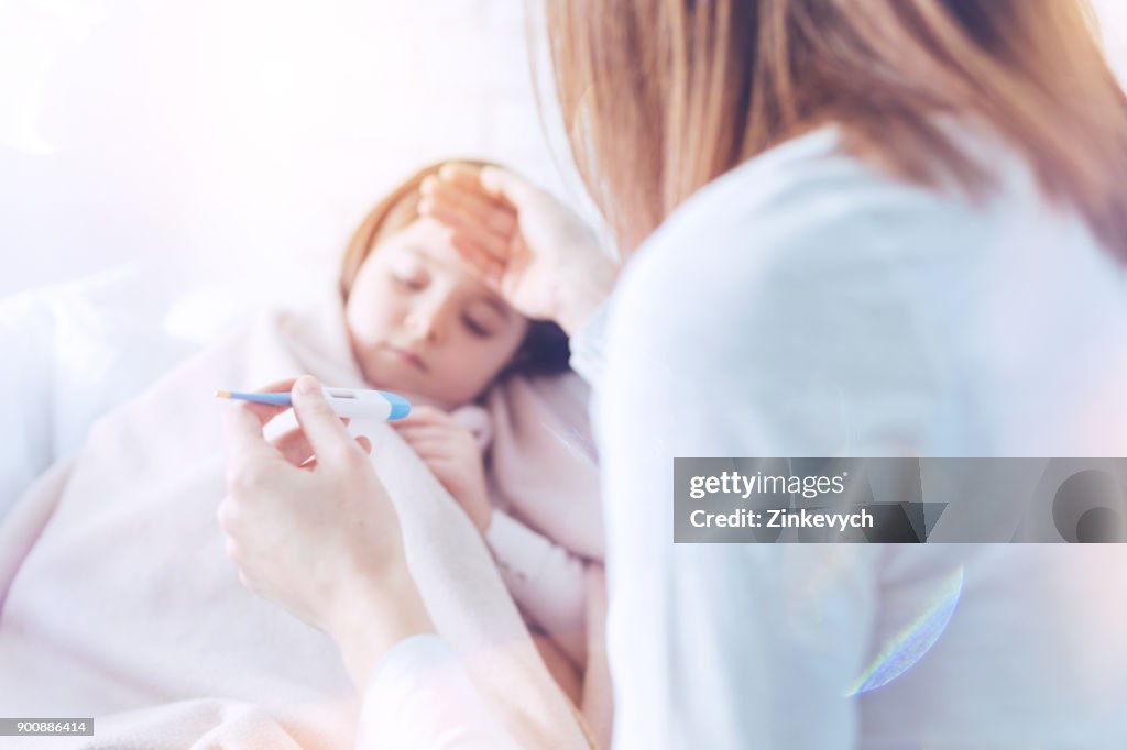 Sick girl lying in her bed under plaid