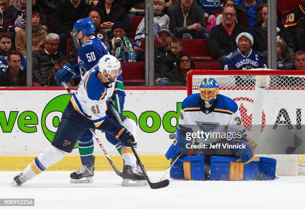 Robert Bortuzzo of the St. Louis Blues and Brendan Gaunce of the Vancouver Canucks look on as Jake Allen of the St. Louis Blues makes a save during...