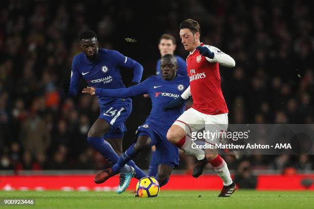 Mesut Ozil of Arsenal competes with N'Golo Kante and Tiemoue Bakayoko of Chelsea during the Premier League match between Arsenal and Chelsea at...